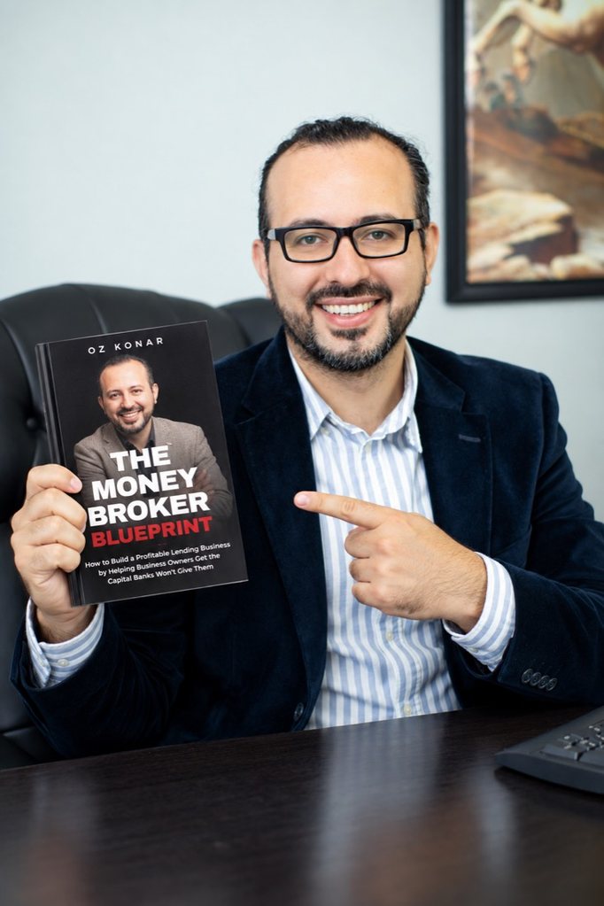 Oz Konar holding his book, The Money Broker Blueprint
